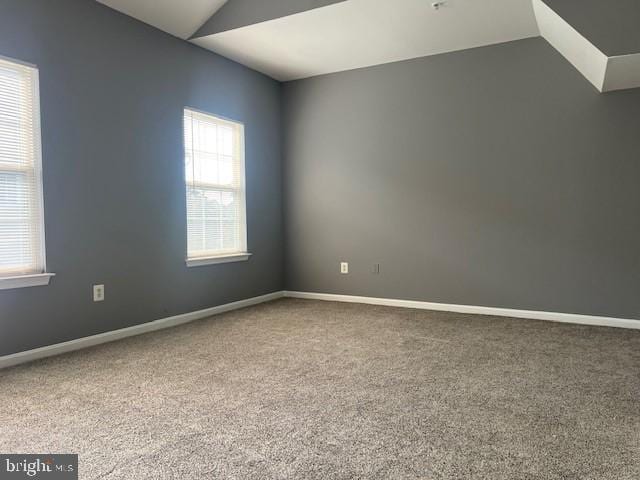 carpeted spare room featuring lofted ceiling