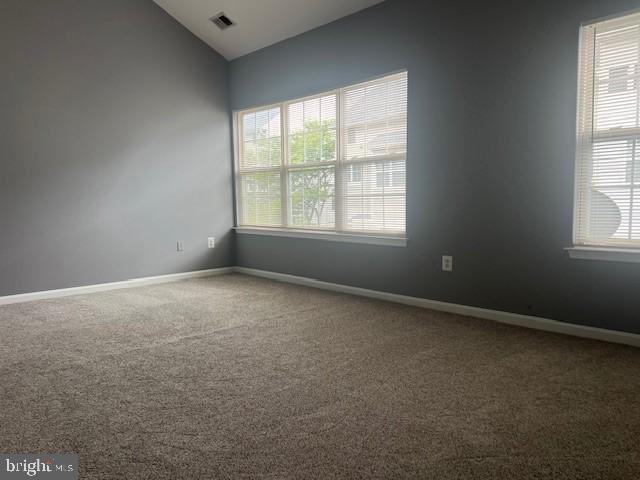 spare room featuring carpet flooring and vaulted ceiling