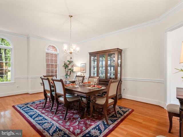 dining room featuring light wood-type flooring, a chandelier, and ornamental molding