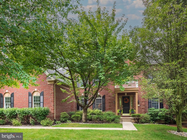 view of front of house featuring a front yard and a balcony