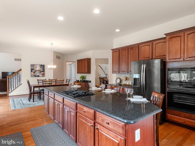 kitchen featuring black appliances, a notable chandelier, a center island, and light hardwood / wood-style floors