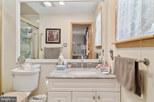 bathroom featuring vanity, toilet, and a shower with door