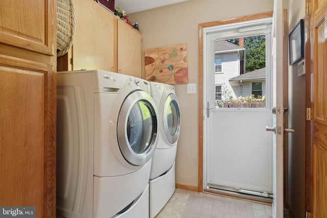 laundry area featuring washer and clothes dryer, light tile patterned floors, and cabinets