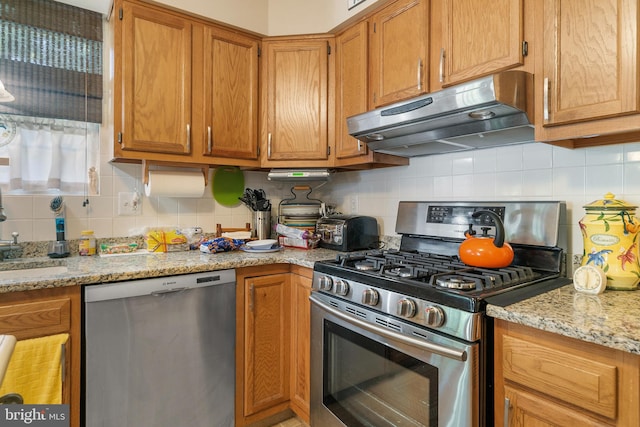 kitchen featuring appliances with stainless steel finishes, backsplash, light stone countertops, and sink