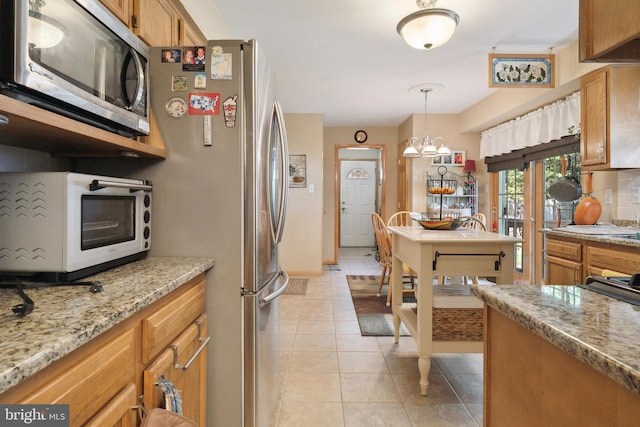 kitchen featuring pendant lighting, a chandelier, light stone counters, light tile patterned flooring, and tasteful backsplash