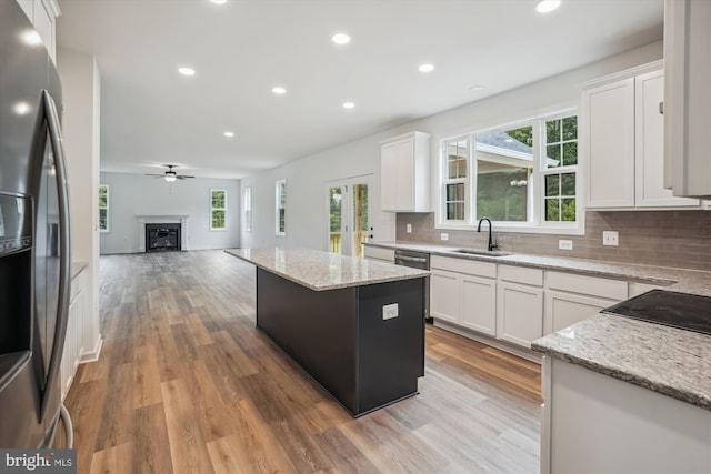 kitchen with sink, light hardwood / wood-style flooring, stainless steel fridge, and backsplash