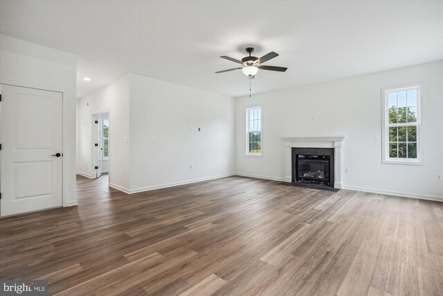 unfurnished living room featuring a fireplace, wood-type flooring, and ceiling fan