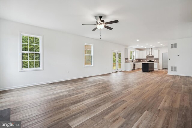 unfurnished living room with plenty of natural light, ceiling fan, and light hardwood / wood-style floors