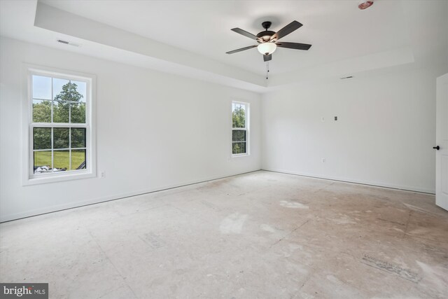 spare room featuring ceiling fan, plenty of natural light, and a tray ceiling