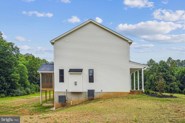 view of side of home with a yard, a sunroom, and central AC unit