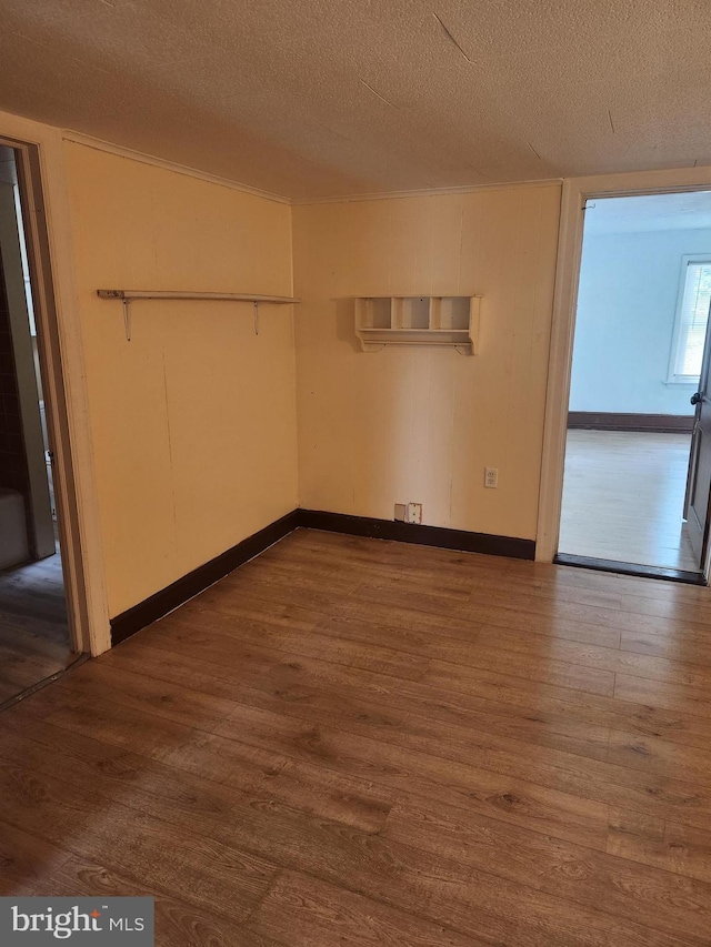 empty room with wood-type flooring and a textured ceiling