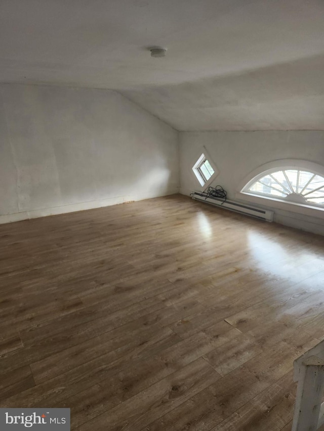 additional living space featuring a baseboard radiator, lofted ceiling, and hardwood / wood-style flooring