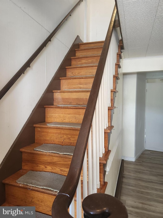 stairway with a textured ceiling and wood-type flooring