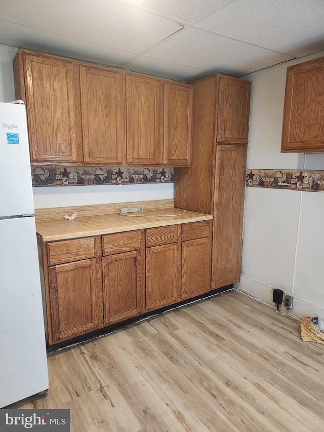 kitchen with white fridge, light hardwood / wood-style floors, and a paneled ceiling