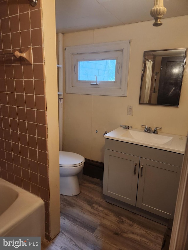 full bathroom featuring vanity, washtub / shower combination, hardwood / wood-style flooring, and toilet