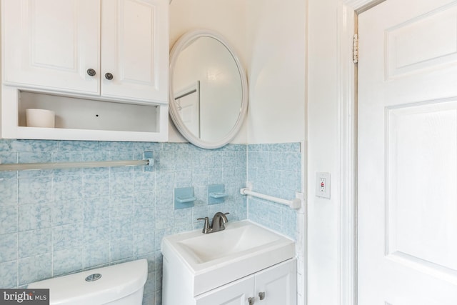 bathroom with vanity, toilet, and tile walls