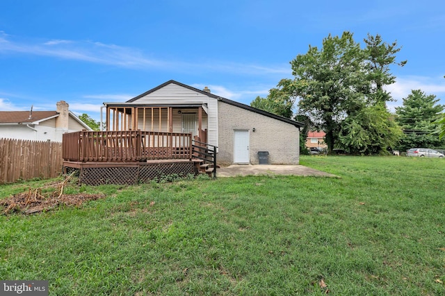 rear view of property with a wooden deck and a lawn