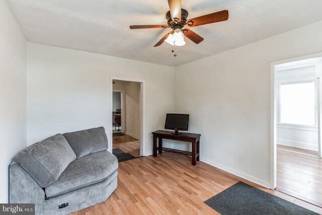 living area with light hardwood / wood-style flooring and ceiling fan