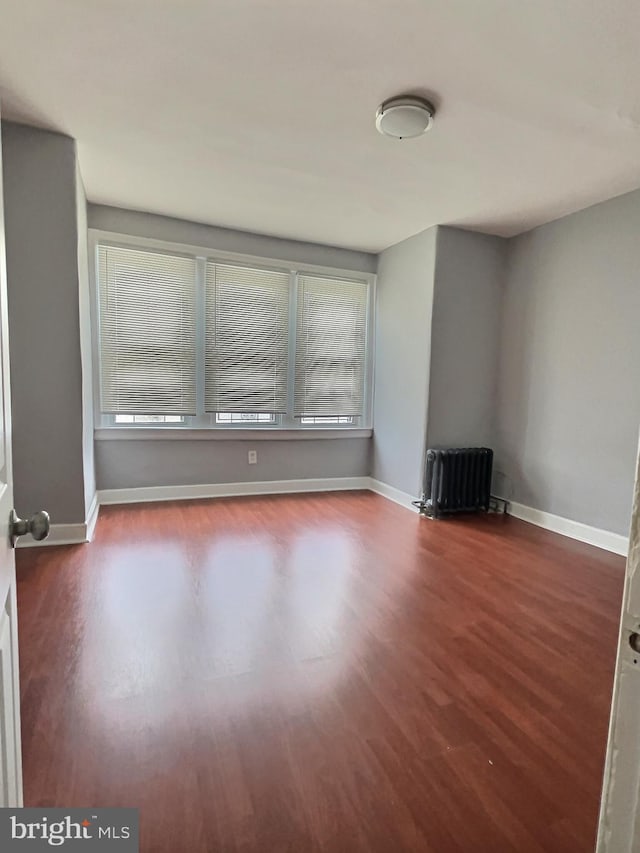 spare room featuring radiator and hardwood / wood-style flooring