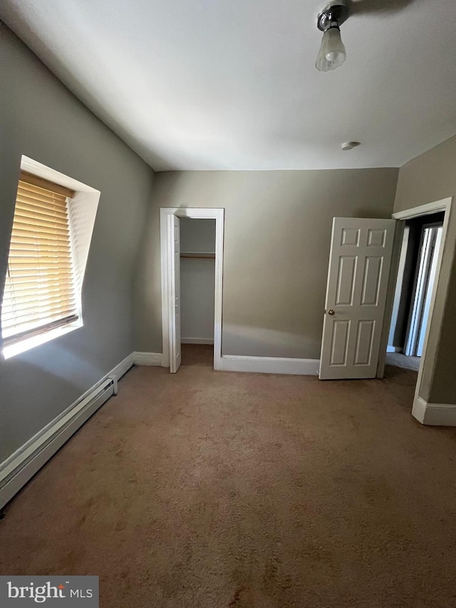 unfurnished bedroom with a baseboard radiator, carpet, and a closet