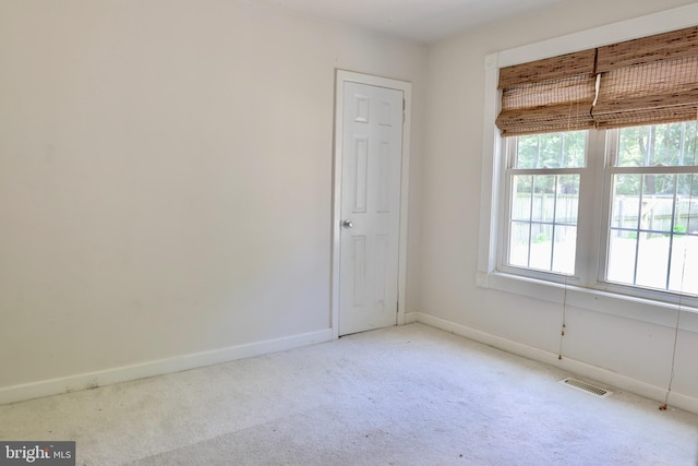 unfurnished room featuring visible vents, light carpet, and baseboards