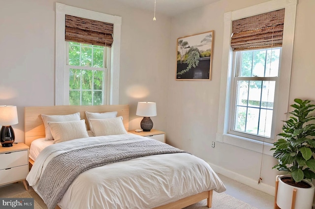 bedroom featuring multiple windows, baseboards, and light colored carpet