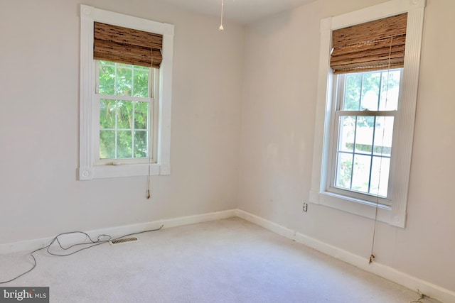 carpeted spare room featuring visible vents and baseboards