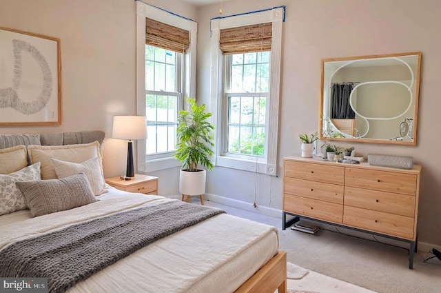 bedroom with multiple windows, baseboards, and light colored carpet