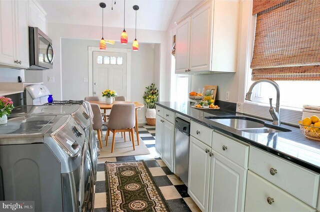 kitchen featuring lofted ceiling, sink, white cabinetry, appliances with stainless steel finishes, and washer and dryer