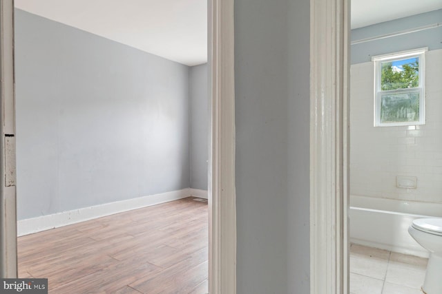 bathroom featuring tiled shower / bath combo, hardwood / wood-style floors, and toilet