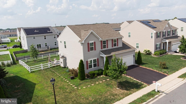 view of front facade with a front lawn, solar panels, and a garage