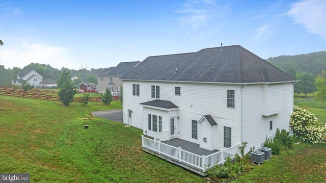 rear view of property with central AC unit and a yard