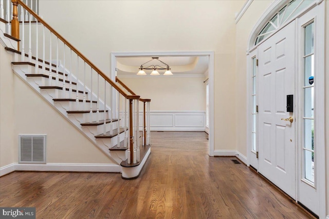 foyer entrance featuring wood-type flooring, a raised ceiling, and ornamental molding