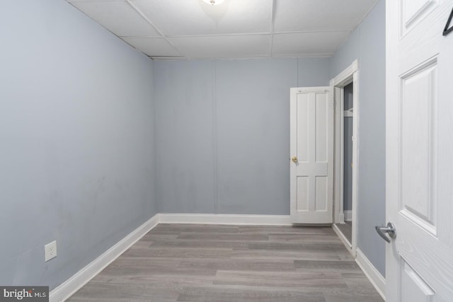 empty room with a drop ceiling and light hardwood / wood-style flooring