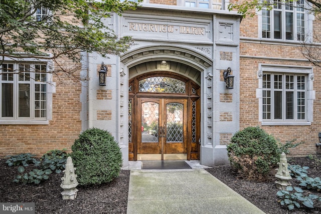 view of exterior entry featuring french doors and brick siding