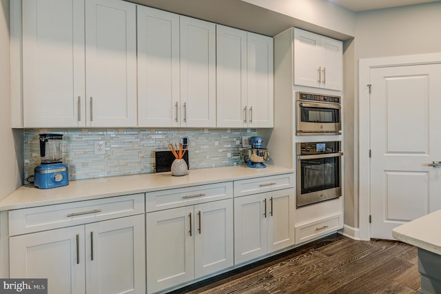 kitchen with stainless steel double oven, decorative backsplash, dark wood-type flooring, and white cabinets