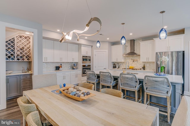 kitchen featuring a spacious island, pendant lighting, white cabinets, and wall chimney exhaust hood