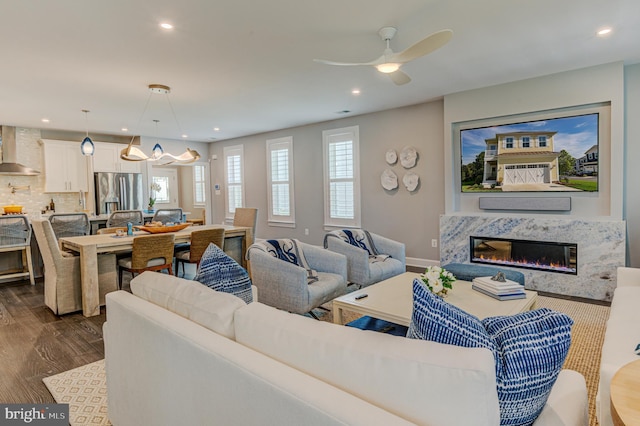 living room with ceiling fan, a high end fireplace, and dark hardwood / wood-style flooring