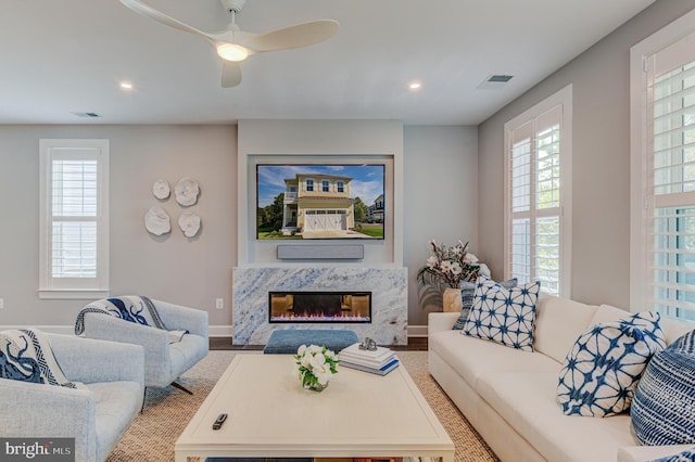 living room featuring a premium fireplace and ceiling fan