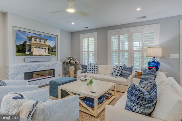 living room featuring ceiling fan and a high end fireplace