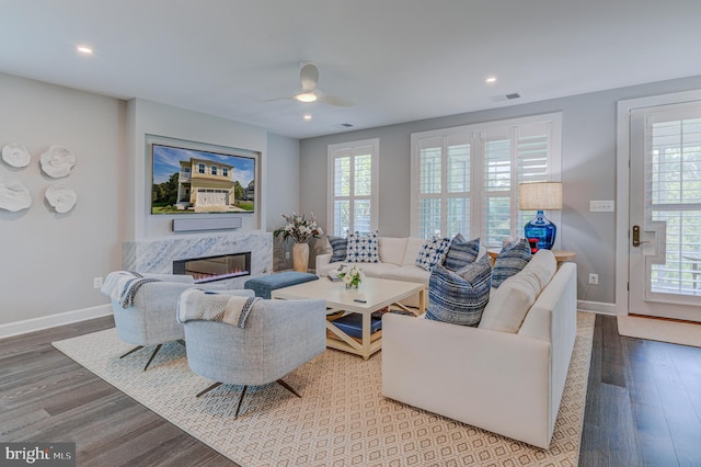 living room featuring hardwood / wood-style flooring, plenty of natural light, a premium fireplace, and ceiling fan