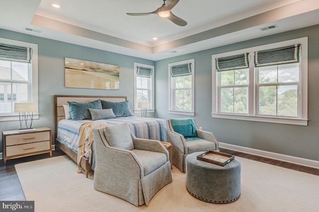 bedroom with ceiling fan, a raised ceiling, and wood-type flooring