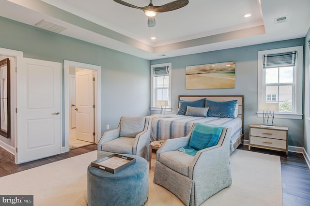 bedroom with dark wood-type flooring, a raised ceiling, and ceiling fan