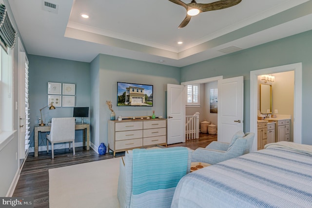 bedroom featuring dark hardwood / wood-style floors, ensuite bath, a tray ceiling, and ceiling fan