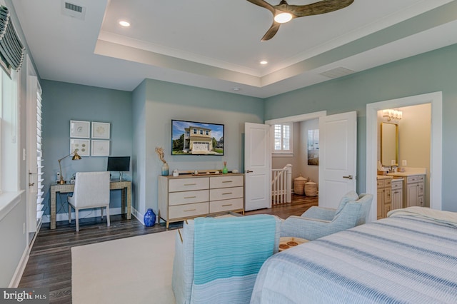 bedroom featuring ceiling fan, connected bathroom, dark hardwood / wood-style flooring, and a raised ceiling