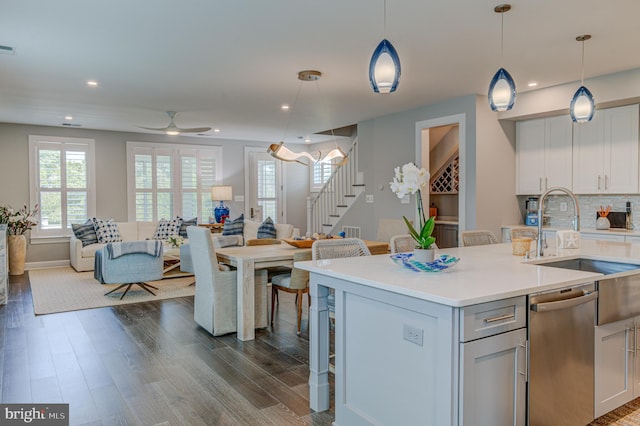 kitchen featuring sink, wood-type flooring, a center island with sink, dishwasher, and pendant lighting