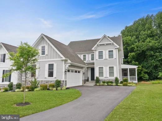 view of front of property featuring board and batten siding, a front yard, and aphalt driveway