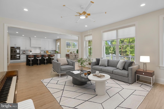 living area with baseboards, plenty of natural light, light wood-style flooring, and recessed lighting