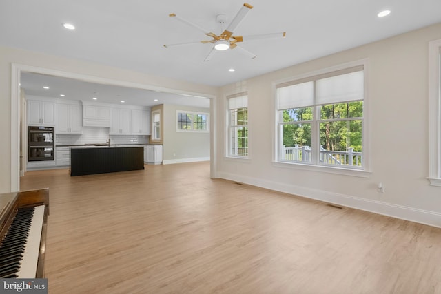 unfurnished living room featuring light wood-style flooring, visible vents, and baseboards