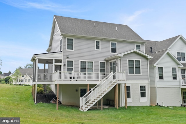 back of house featuring roof with shingles, stairway, a wooden deck, and a lawn